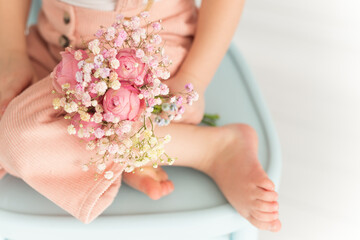A bouquet of flowers in the hands of a girl sitting on a chair