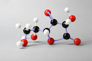 Molecule of vitamin C on light grey background. Chemical model