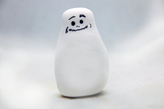 White figurine with eyes and a smile on a white background