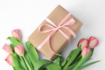 Obraz na płótnie Canvas Beautiful gift box with bow and pink tulips on white background, above view