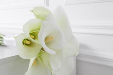 Beautiful calla lily flowers tied with ribbon on white table, closeup