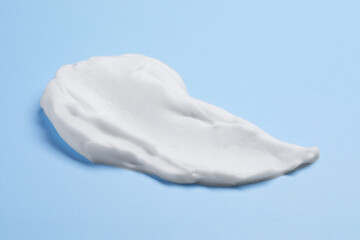 Sample of shaving foam on light blue background, closeup
