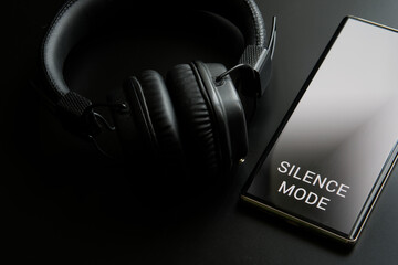 Mobile phone - a smartphone with activated silence mode and black wireless headphones. Barring...