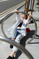 Portrait of young carefree woman wearing street style fashion outdoors in urban setting and kicking up to camera. Photo framing