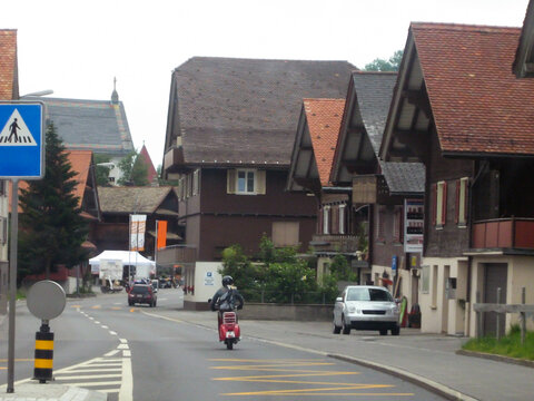 A motorcyclist rides down the street of a medieval old town in Germany. Houses with tiled roofs.