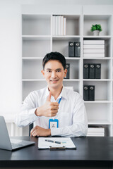 Happy Asian male businessman giving a thumbs up gesture of approval and success.