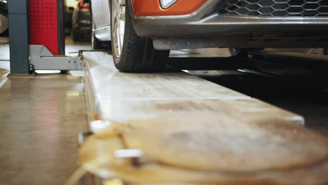 Close up view of service lift car. The car pulls into a modern service station. Transport service concept. Slow motion. Auto mechanic repairing car. The car driving onto the lift.