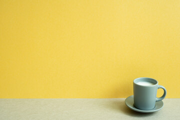 Cup of milk on gray table. yellow wall background. copy space