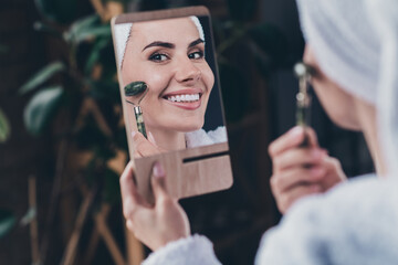Photo of beautiful lady doing home morning procedures after shower making face peeling quartz massager joyful hold mirror indoors