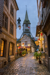 Medieval street with lights and half-timbered houses and the wooden church of Saint-Catherine's...