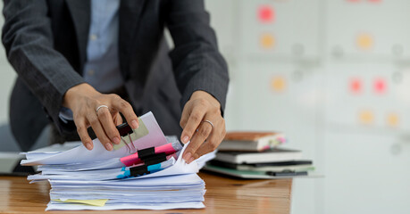 Businesswoman hands working in Stacks of paper files for searching and checking unfinished document...