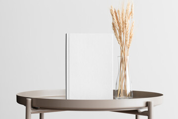 White book mockup with a wheat flower decoration on the beige table.