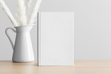 White book mockup with a pampas decoration on the wooden table.