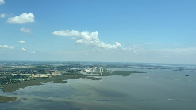 Real approach to Venice international airport shot from an airplane cabin. An unique pilot&rsquo;s point of view. Sunny day and blue sky with few tiny clouds.