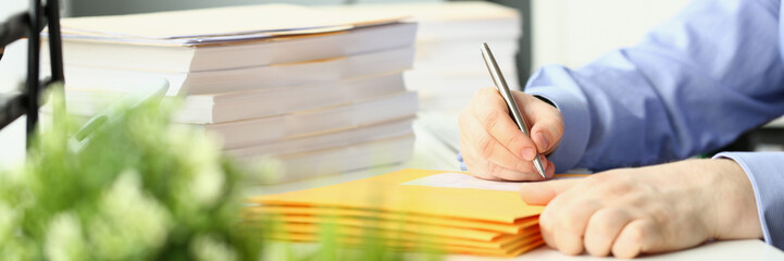 Clerk fills yellow envelopes with mail in office. Sending business correspondence concept