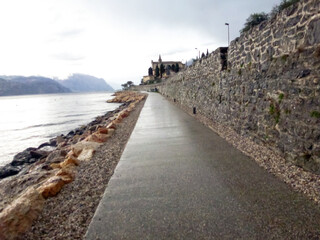 Promenade near sea bay with stone wall and long road in perspective