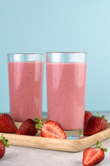 Strawberry smoothie or milkshake with berries on a blue background. Summer beverages. Copy space.