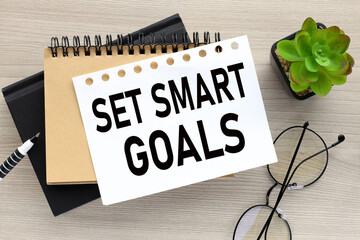 the words Set smart goals on a white page on two notepads