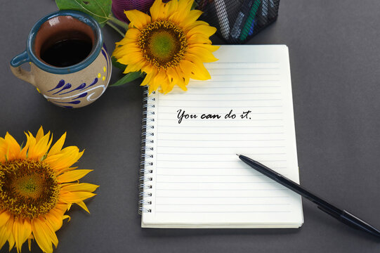 Motivational words on a notebook - You can do it. With pen, sunflowers and a cup of coffee. 
