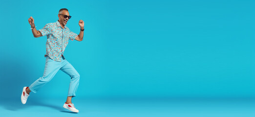 Fototapeta na wymiar Dancing man on summer vacation, active, wearing shirt, pants, shoes, sunglasses, isolated on a blue background.text copyspace banner background. Generative ai