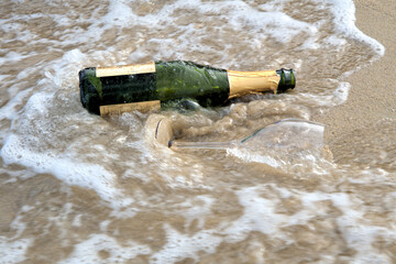 Sea waves brown sand empty champagne bottle wine glass