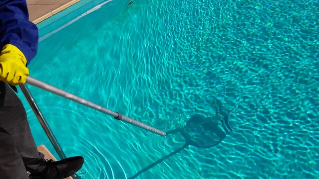 Cleaning the pool from debris with a special mesh. Maintenance of the pool, clear water with a blue tint. Selective focus. Dirty pool with fine dirt on the bottom. Cleaning concept