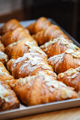 Sprinkle the finished croissants on a baking sheet with almond flakes and powdered sugar