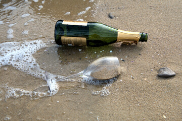 Sea waves brown sand empty champagne bottle wine glass