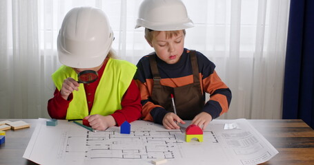 Junior schoolgirl and preschooler imitate role of builders. Girl looks with magnifying glass at...