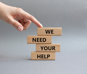 We need your help symbol. Wooden blocks with words We need your help. Beautiful grey background. Businessman hand. Business and We need your help concept. Copy space.