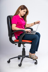 Fototapeta na wymiar Indian woman sitting on chair and using laptop