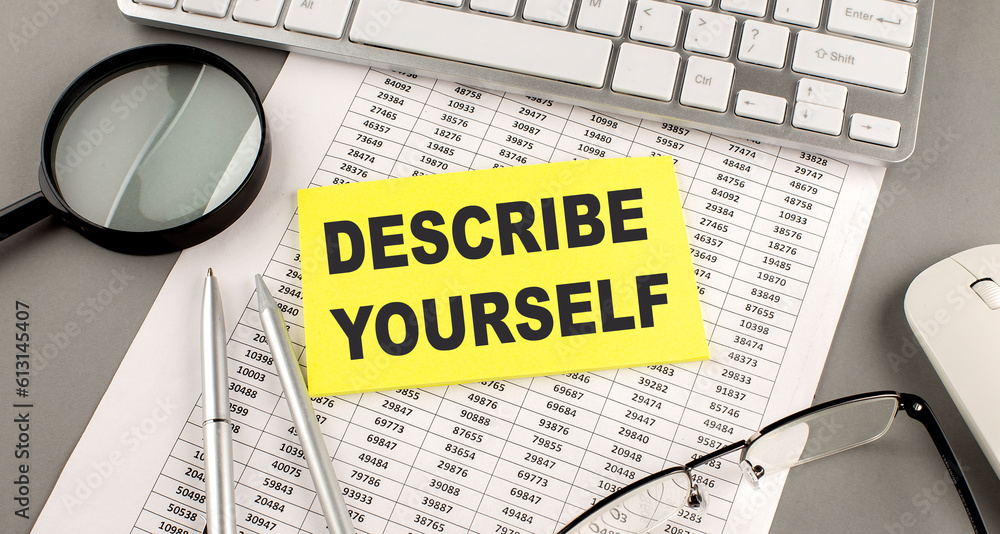 Poster describe yourself text written on a sticky on chart with keyboard and magnifier