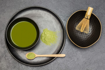 Bamboo whisk in a bowl. Wooden spoon with matcha powder