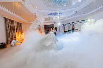 the first dance at the wedding of the bride and groom in an elegant restaurant with great lighting and atmosphere. Heavy smoke