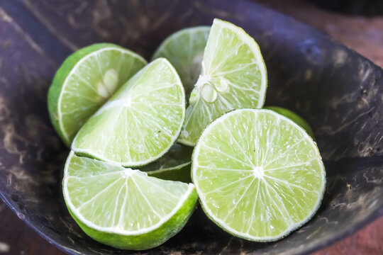 Close-up photo of slices green lime in a wooden bowl, usually served with other dishes like traditional Javanese chicken soup or Soto. This lime also used as herbal medicine and contains vitamin C.