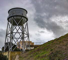 Water tower that supplies the federal prison on Alcatraz Island of the United States of America in the bay of the city of San Francisco, California, USA. Surveillance under a cloudy sky. Jail concept.