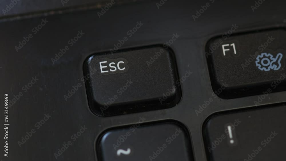 Aufkleber finger presses the esc button on the laptop keyboard.