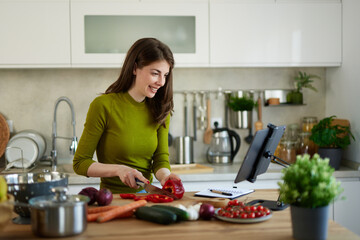 Woman cooking at home following an online recipe on digital tablet