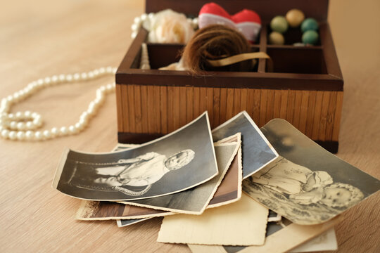 dear to heart memorabilia in an old wooden box, a stack of retro photos, a wooden rosary, vintage photographs of 1960, concept of family tree, genealogy, childhood memories