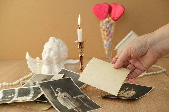 stack of vintage photos female hand, romantic still life in love style, in a glass vase red hearts on sticks, colorful candies, candles burning, concept of family tree, genealogy, childhood memories