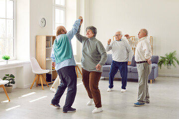 Happy retired senior people having a party, dancing and having fun together. Elderly men and woman dancing at home or in a retirement community center. Old age and leisure concept