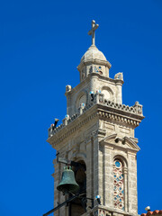 Church tower with bell against blue sky. Fanes, Rhodes island, Greece. Close up.