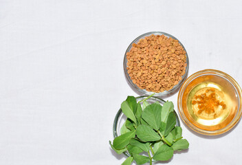 Fenugreek leaves with seeds and oil over white background. Concept of Indian ayurvedic medicine for blood suger, and damage hair and hairfall control