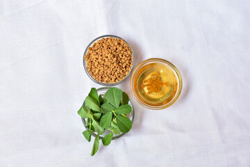 Fenugreek leaves with seeds and oil over white background. Concept of Indian ayurvedic medicine for...