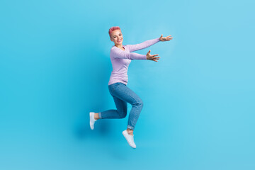 Fototapeta na wymiar Full length photo of young girl pink dyed hair wear denim jeans purple shirt hugs embrace empty space isolated on blue color background