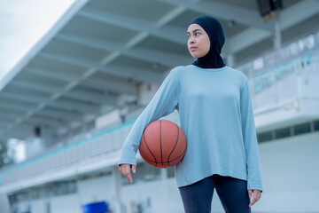 Young asian muslim girl teen wearing hijab going to play basketball on the outdoor court in the...