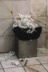 Bucket full of paper towels in a WC
