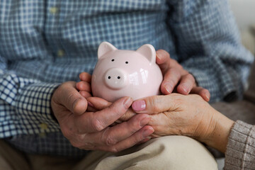 Saving money investment for future. Senior adult mature couple hands holding piggy bank with money...