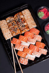 Asian sushi. Philadelphia with salmon, shrimp, eel and sesame on a dark background. Food delivery. View from above.