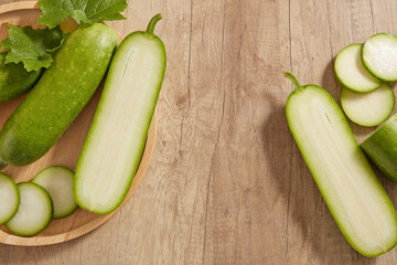 Winter melon cut in half and slices arranged on wooden tray and wooden table. Vacant space on the table for product presentation extracted from Winter melon (Benincasa hispida)